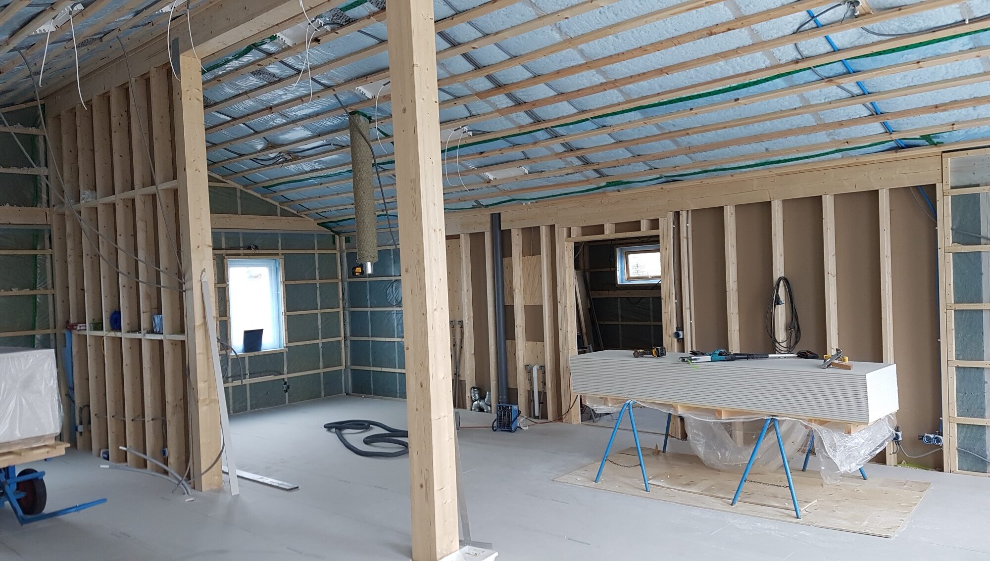 20200514_150110_resized Insidan av ett hus som håller på att byggas upp, gipsskivor som ligger på ett arbetsbord.