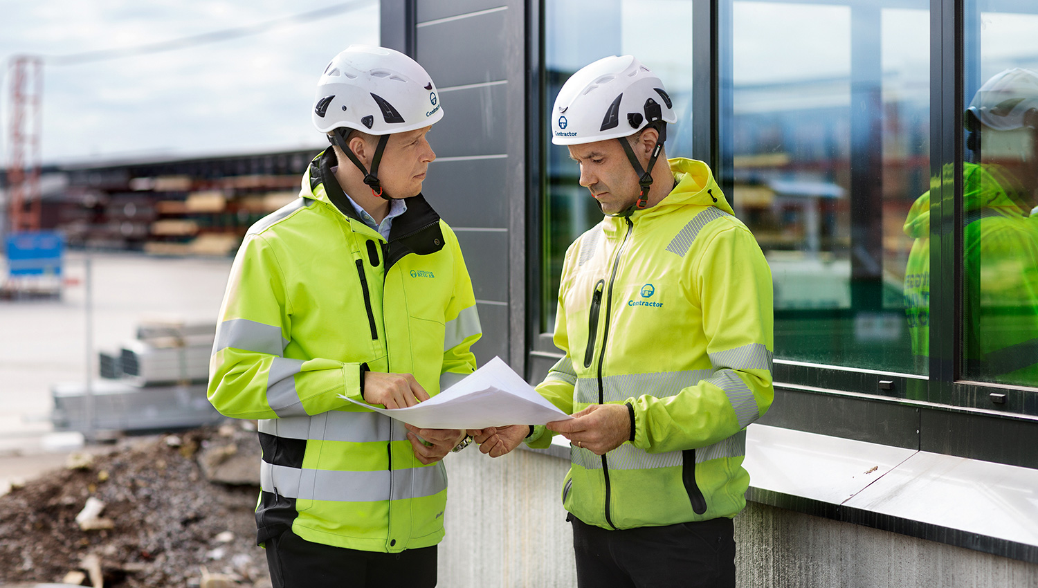 Två män från Contractor som står och pratar kring en ritning över Umeå Polishus