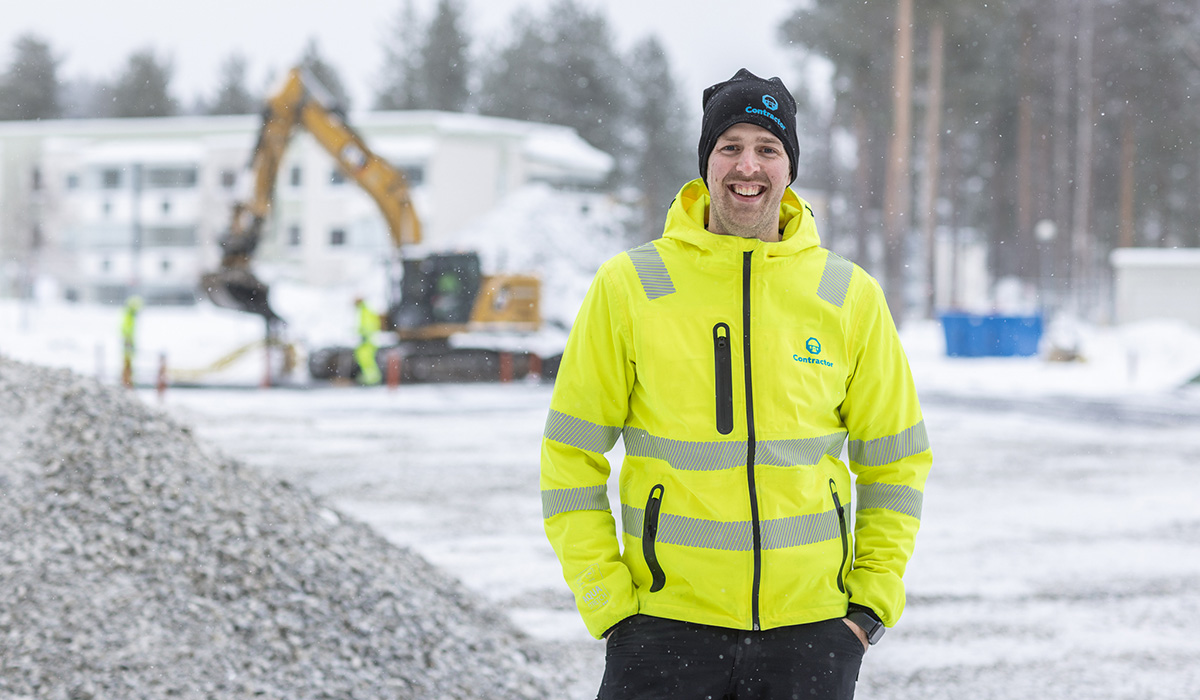 Markarbetare från Contractor som står på en arbetsplats med en grävare i bakgrunden.