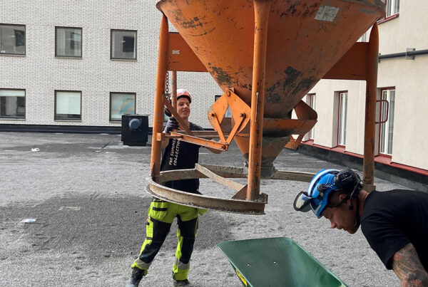 Två markarbetare som använder en betongbasker på NUS projektet